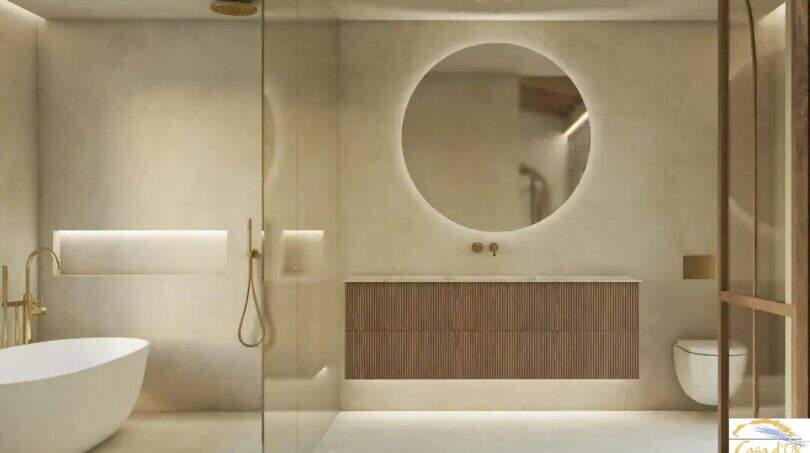 Moderno cuarto de baño de lujo de la finca de Artà, con bañera independiente, espejos redondos y grifería dorada.