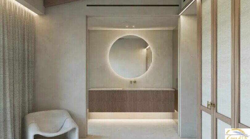 El elegante cuarto de baño de la Finca Artà, con un espejo redondo, un lavabo de madera y un ambiente acogedor