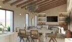 Salón-comedor diáfano de la Finca Artà, con techo de vigas de madera, sillas de ratán y un ambiente mediterráneo.