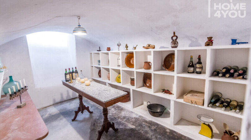 Gewölbekeller mit weißen Einbauregalen, Weinflaschen, Keramik und antikem Granittisch im Herrenhaus Porreres