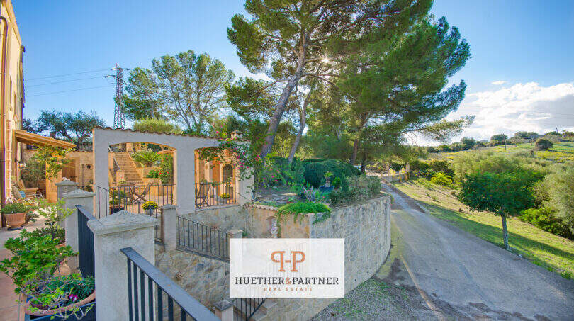 Außenbereich der Finca Son Macià mit gepflegtem Steingarten, Terrasse, Pinien und idyllischer Landschaftskulisse.