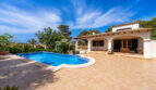 Villa de estilo mediterráneo en Cala Murada con una gran piscina, terraza y arcadas bajo el cielo azul.