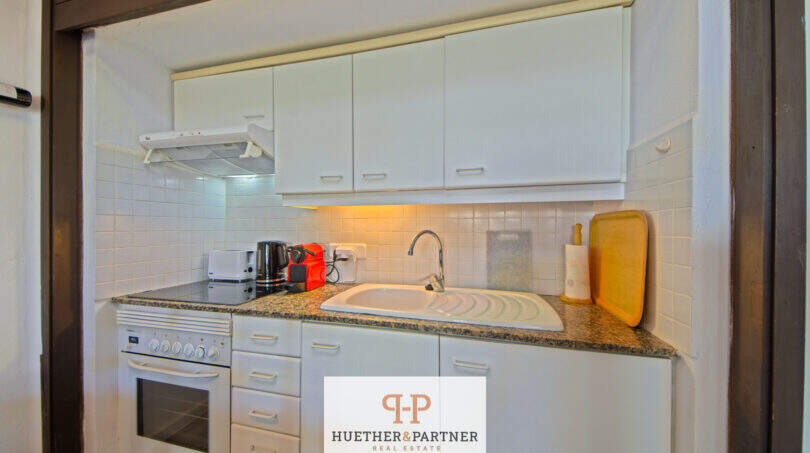 Kompakte Küche mit weißen Schränken, Granitarbeitsplatte, Herd und Spüle in Terrassen-Wohnung, Cala d'Or