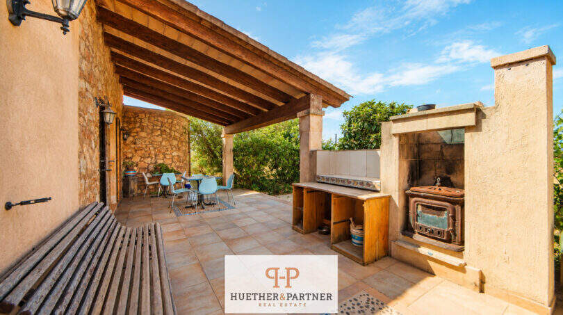 Überdachte Terrasse der Finca mit Grillstation, Holzbalken-Dach und Esstisch-Bereich umgeben von Natur.