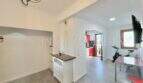 Luminosa zona de estar con suelo de madera, cocina abierta en rojo y área de fitness en apartamento renovado en Palma