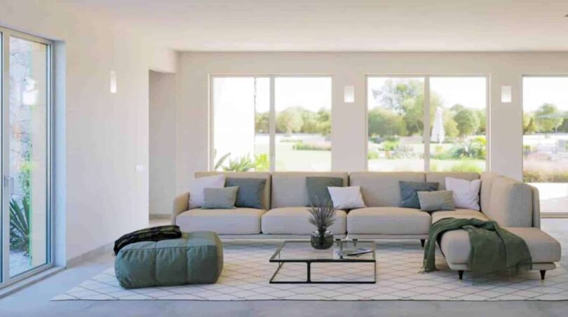 Helles Wohnzimmer der Finca Cala Murada mit Panoramafenstern, modernem Sofa und Gartenblick
