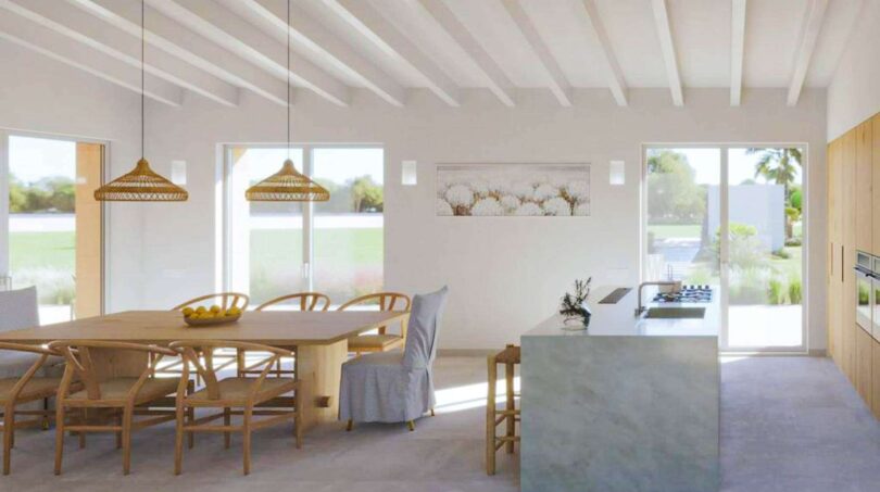 Helles Wohn-Esszimmer der Finca in Cala Murada mit Holztisch, Kücheninsel und großen Fenstern