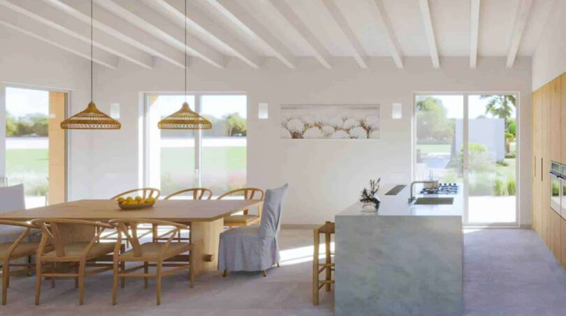 Helles Esszimmer mit Holztisch, Kücheninsel und Panoramafenstern der Finca in Cala Murada, Manacor.