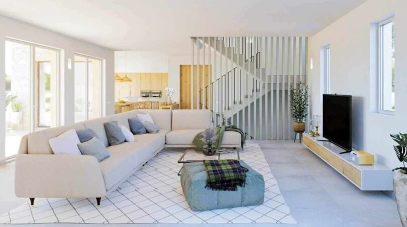 Helles Wohnzimmer der Finca Cala Murada mit Sofa, TV-Wand, offener Küche und moderner Treppe.