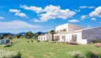 Moderne Finca in Cala Murada mit weitläufigem Grüngarten, Natursteinfront und Blick auf Hügel