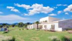 Moderne Finca in Cala Murada, Manacor – helles Steingebäude mit Terrasse, weitläufigem Grünbereich und Palmen.