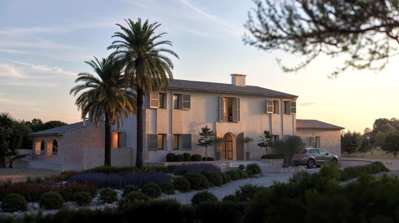 Außenansicht der Luxusfinca in Ses Salines mit Palme, mediterranem Garten und elegantem Eingangsbereich bei Abenddämmerung.