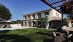Luxusfinca Ses Salines: Steinvilla mit Pool, Pergola, Gartenlounge und üppigem Grün unter blauem Himmel.
