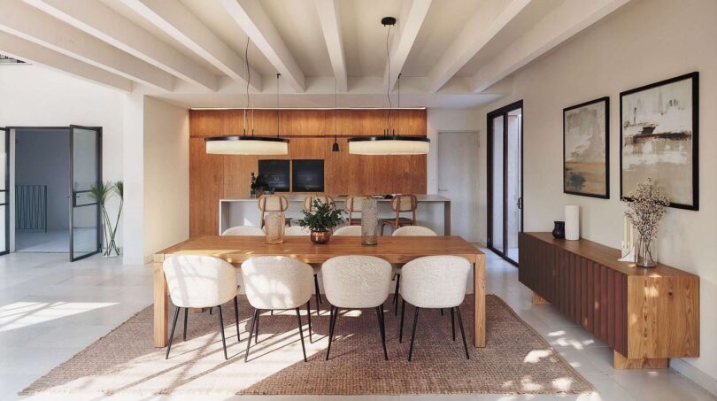 Heller Wohn-Essbereich der Luxusfinca in Ses Salines mit Holztisch, weißen Polsterstühlen und moderner Küche.