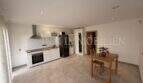 Cocina abierta con muebles de cocina blancos empotrados, mesa de comedor y suelo de baldosas en apartamento de huéspedes, villa Marratxí