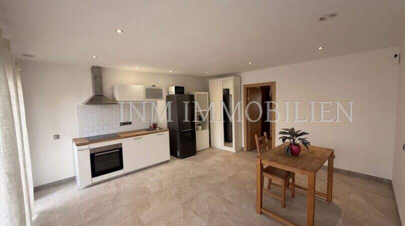 Cocina abierta con muebles de cocina blancos empotrados, mesa de comedor y suelo de baldosas en apartamento de huéspedes, villa Marratxí