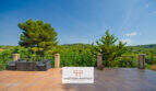 Weitläufige Terrasse der Finca Son Macià mit Lounge-Möbeln, Schmiedeeisenzaun und Panoramablick ins grüne Hügelland