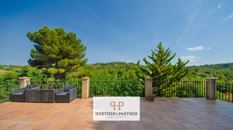 Weitläufige Terrasse der Finca Son Macià mit Lounge-Möbeln, Schmiedeeisenzaun und Panoramablick ins grüne Hügelland