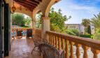 Terraza cubierta de la villa de Cala Murada, con arcos, sillas de ratán y vistas a la piscina y al jardín.
