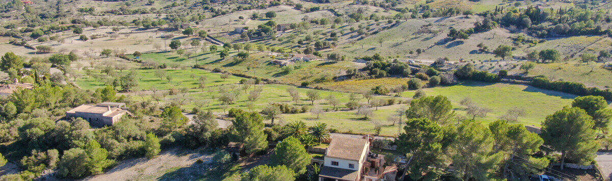Aerial view of Finca Son Macià, nestled among green hills with ocean views and a spacious property.