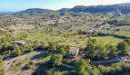 Luftaufnahme einer Finca in Son Macià, umgeben von grüner Landschaft, Feldern und Hügeln mit Meerblick.