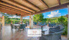Überdachte Terrasse der Finca Son Macià mit Holzbalkendecke, Lounge-Möbeln und Panoramablick ins Grüne.