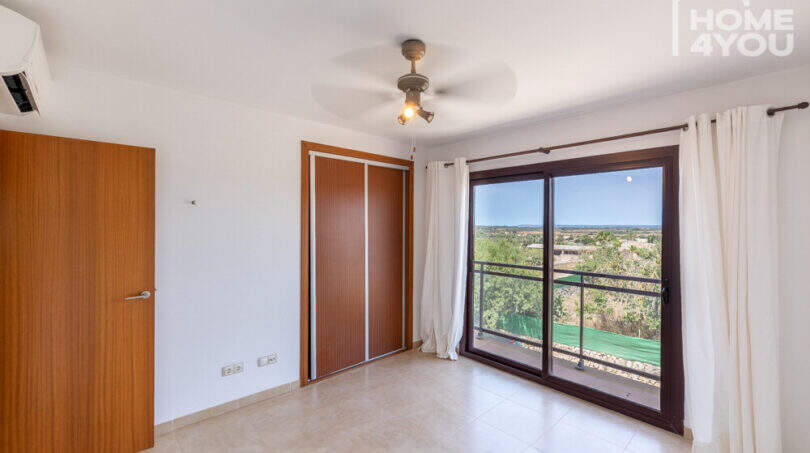 Helles Schlafzimmer mit Einbauschrank, Deckenventilator, Klimaanlage und Balkon mit Grünblick