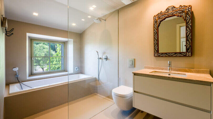 Modernes Badezimmer der Finca in Esporles mit Glasdusche, Einbaubadewanne und orientalischem Spiegel.