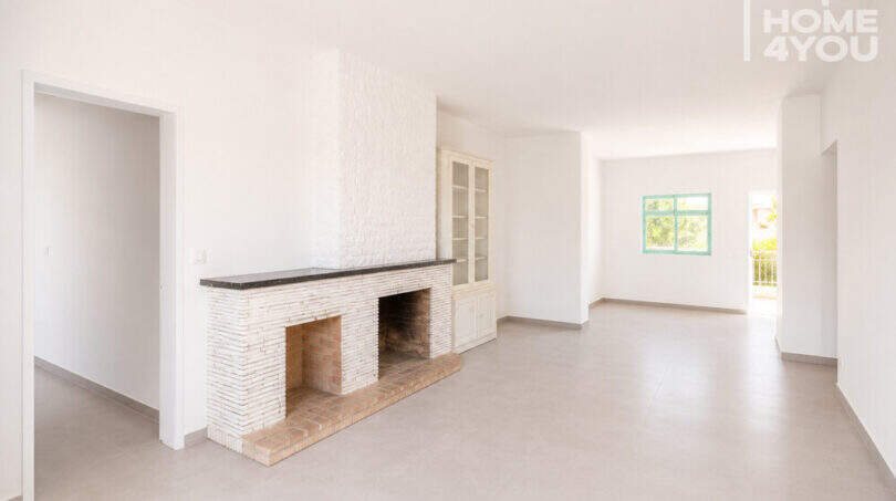 Helles Wohnzimmer mit weißem Kaminofen, Einbauschrank und Terrassenzugang in Erdgeschosswohnung Cala Llombards