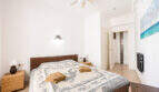 Helles Schlafzimmer mit Doppelbett, Rattan-Elementen, Deckenventilator und Meerblick-Bild in Ses Salines
