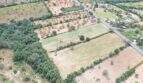 Fotografía aérea de un terreno urbanizable en Felanitx con campos, árboles y una calle en un entorno rural.