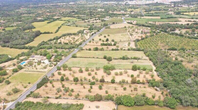 Fotografía aérea de terreno urbanizable en Felanitx con paisaje extenso, campos y calle, vista hacia la ciudad