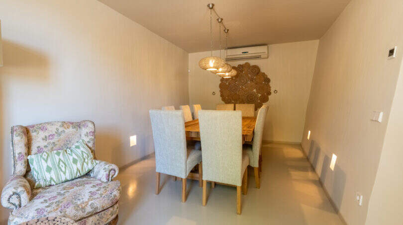 Elegantes Esszimmer mit Holztisch, hellgrünen Stühlen, Kronleuchter und gemütlichem Sessel in Finca Esporles