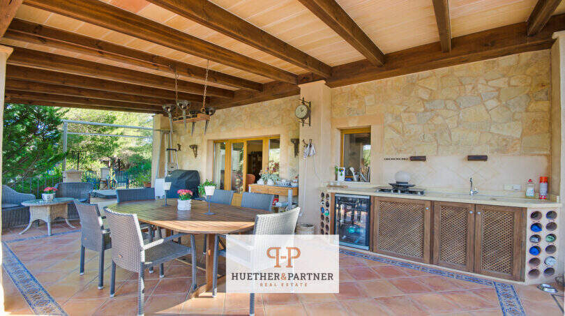 Überdachte Terrasse der Finca Son Macià mit Außenküche, Holzbalkendecke und Natursteinwand