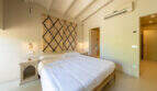 Helles Schlafzimmer der Finca mit Doppelbett, Klimaanlage und Berberteppich als Wanddekoration.