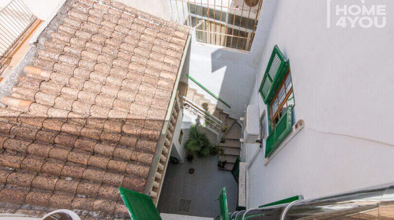 Blick vom Dach auf Innenpatio mit Treppe, Terrakottaziegel, grüne Fensterläden und Klimaanlage des Herrenhauses in Porreres