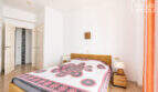 Helles Schlafzimmer mit Doppelbett, Rattanmöbeln und weißen Wänden in Meerblick-Wohnung, Ses Salines