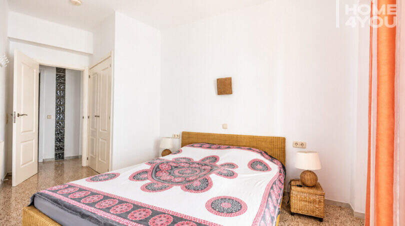 Helles Schlafzimmer mit Doppelbett, Rattanmöbeln und weißen Wänden in Meerblick-Wohnung, Ses Salines
