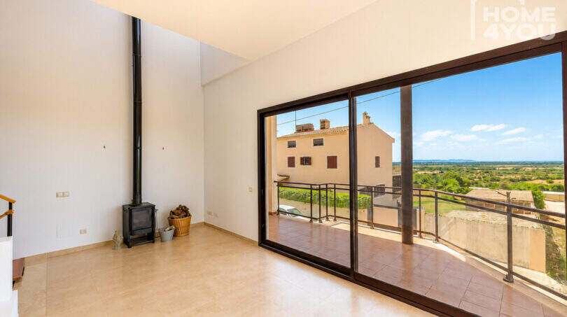 Helles Wohnzimmer mit Kaminofen und großer Glasfront zur Terrasse mit Panoramablick über Ses Salines