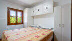 Schlafzimmer mit Doppelbett, Blumendecke, weißen Einbauschränken und Holzfenster mit Gartenblick in Cala Murada