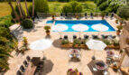 Luftaufnahme Pool & Terrasse des Agroturismo Ses Salines mit Sonnenschirmen, Liegestühlen & üppigem Grün