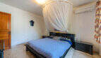 Dormitorio de la villa de Cala Murada con cama de matrimonio, mosquitera, aire acondicionado y suelo de mármol.