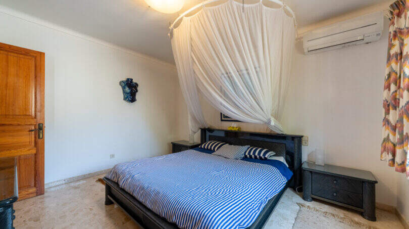 Dormitorio de la villa de Cala Murada con cama de matrimonio, mosquitera, aire acondicionado y suelo de mármol.