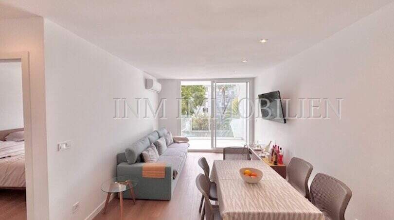 Helles Wohnzimmer mit Sofa, Esstisch und Balkon im renovierten Apartment in Palmanova