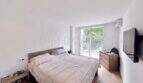 Helles Schlafzimmer mit Doppelbett, Holzmöbeln, TV und Balkonzugang in Apartment Palmanova