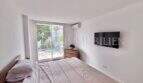 Helles Schlafzimmer mit Doppelbett, Wandmontiertem TV, Klimaanlage und Zugang zur Terrasse in Palmanova