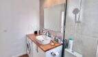 Modernes Badezimmer mit Waschbecken, Waschmaschine und Dusche im renovierten Apartment in Palmanova
