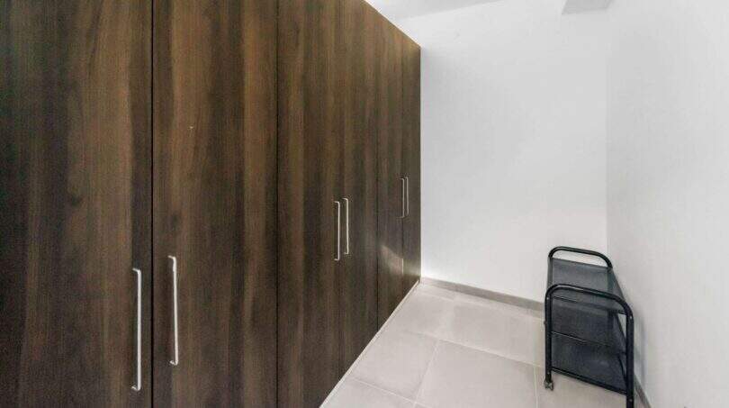 Espacioso vestidor con armarios empotrados de suelo a techo en madera oscura en la casa de ciudad Felanitx