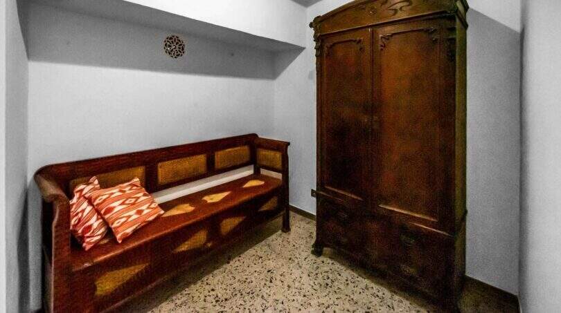 Zona de entrada con armario antiguo de madera y banco rústico, encanto típicamente mallorquín en la casa de ciudad Felanitx