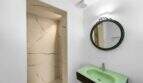 Moderno baño con lavamanos verde, espejo redondo y ducha de mármol en la casa de ciudad Felanitx